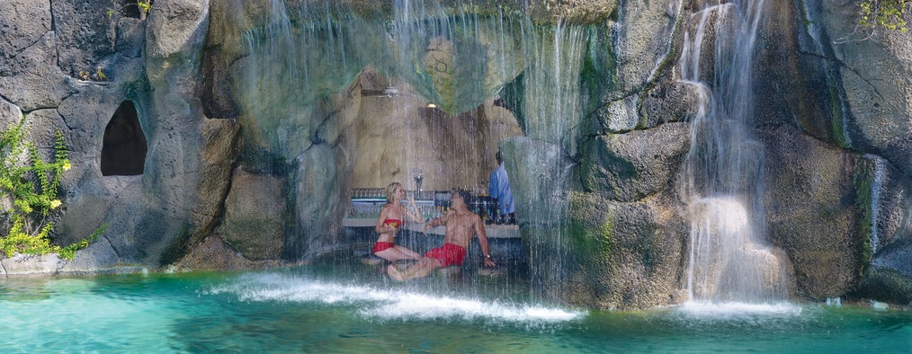 couple swimming under a waterfall