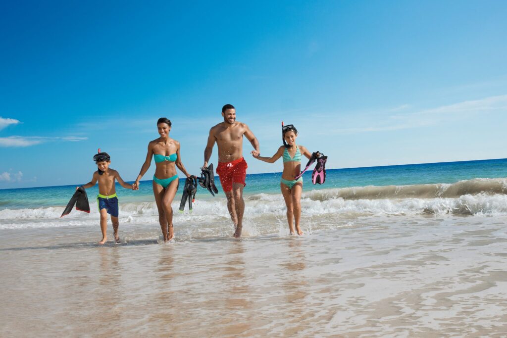 family running through waves on the beach