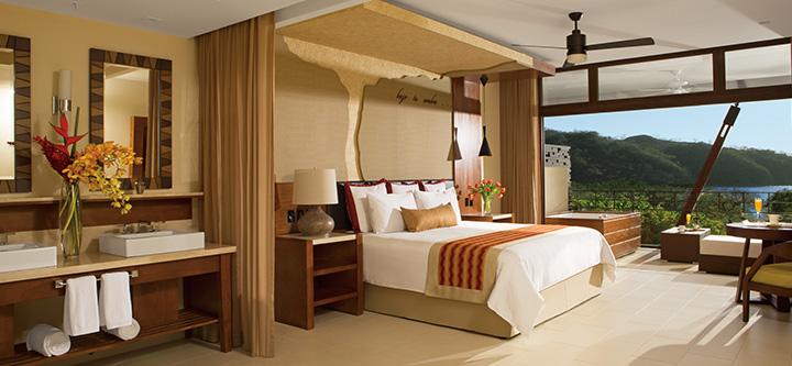 suite with large windows and balcony overlooking rainforest
