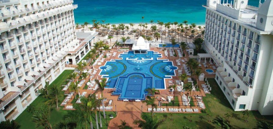 pool and beach adjacent to high rise Riu Palace Aruba