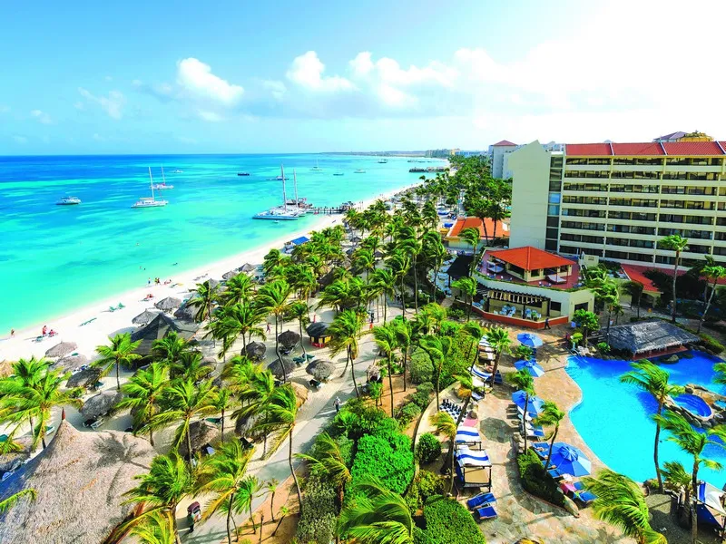 beachside resort full of palm trees on white sand beach in Aruba