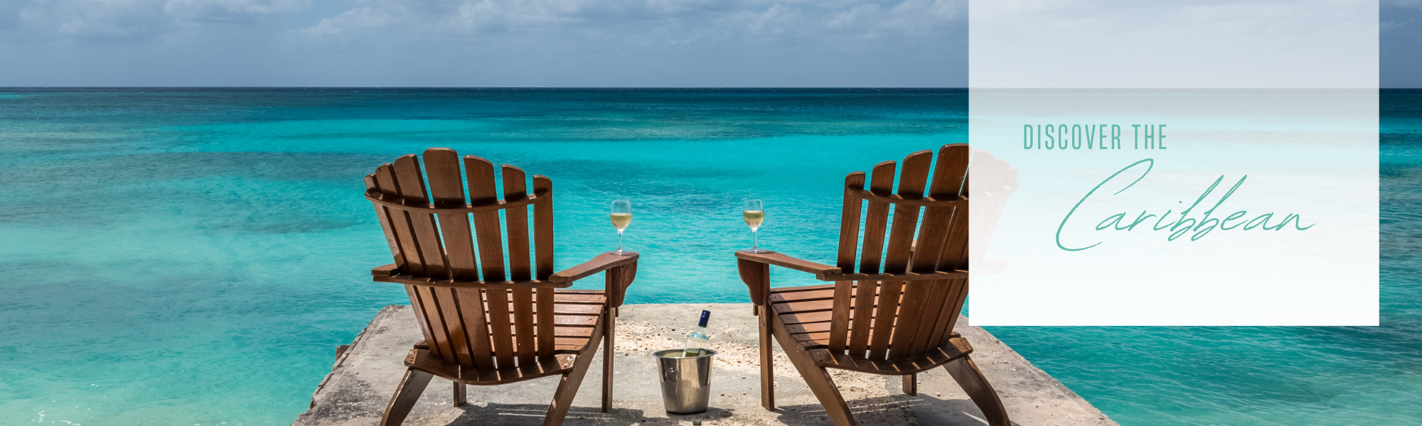 Adirondack chairs with glasses of wine overlooking turquoise Caribbean water 