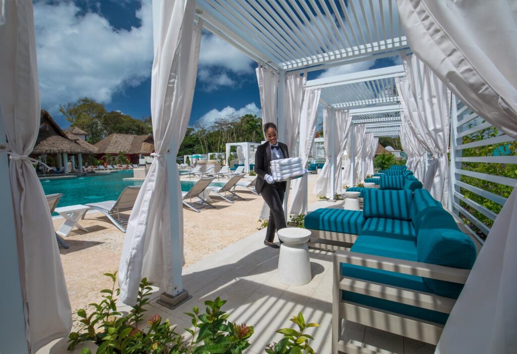 butler placing towels on sun loungers around pool at Sandals Royal Barbados