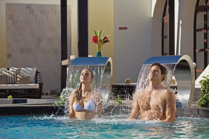 couple standing under modern water feature in pool