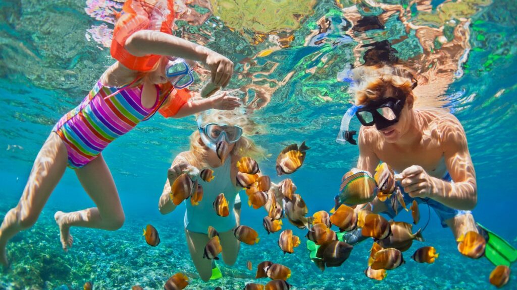 family snorkeling with tropical fish