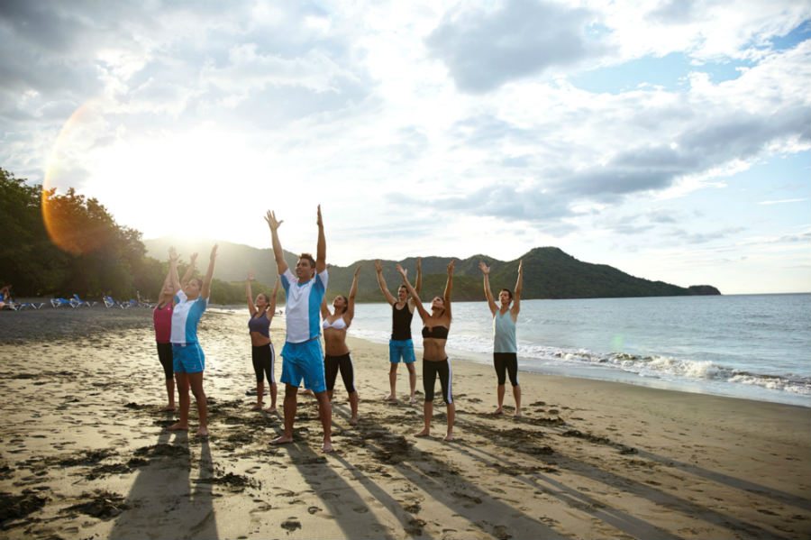 group doing yoga on the beach