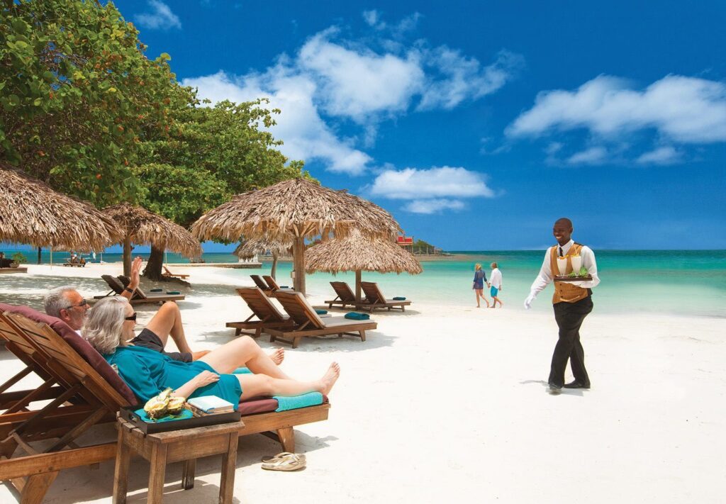 butler bringing drinks to a couple lounging on the beach