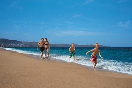 family running through the waves at tropical beach