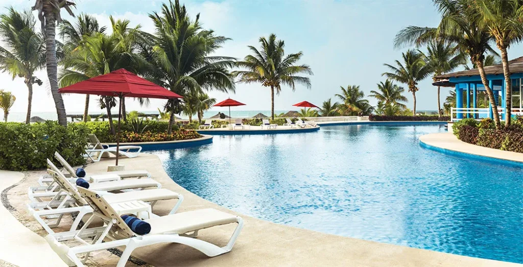 beachside pool with lounge chairs and umbrellas