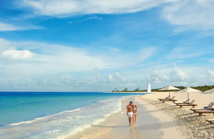 couple walking on white sand beach