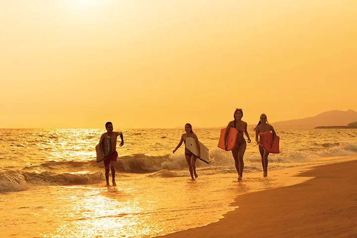 teens running on beach after surfing