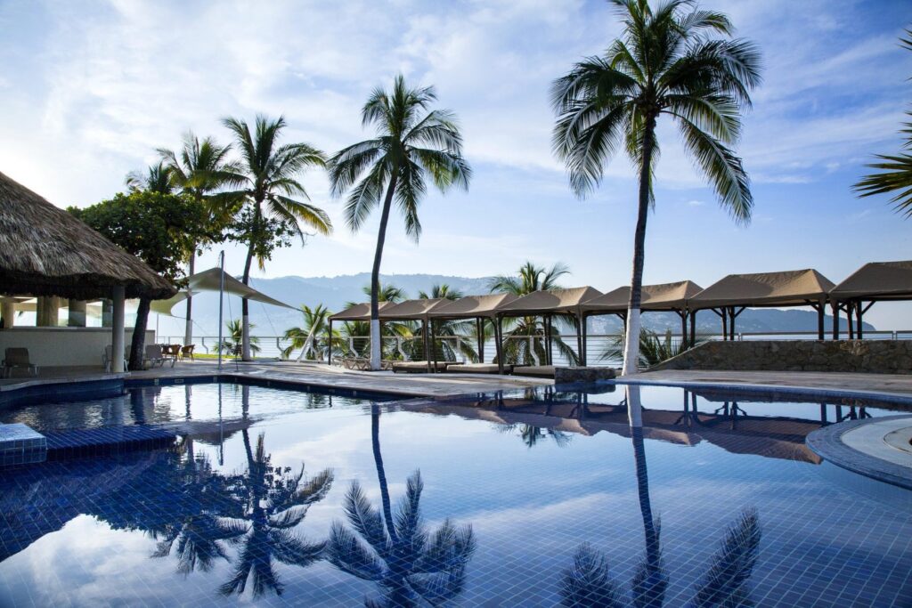 pool surrounded palm trees with mountains in the background